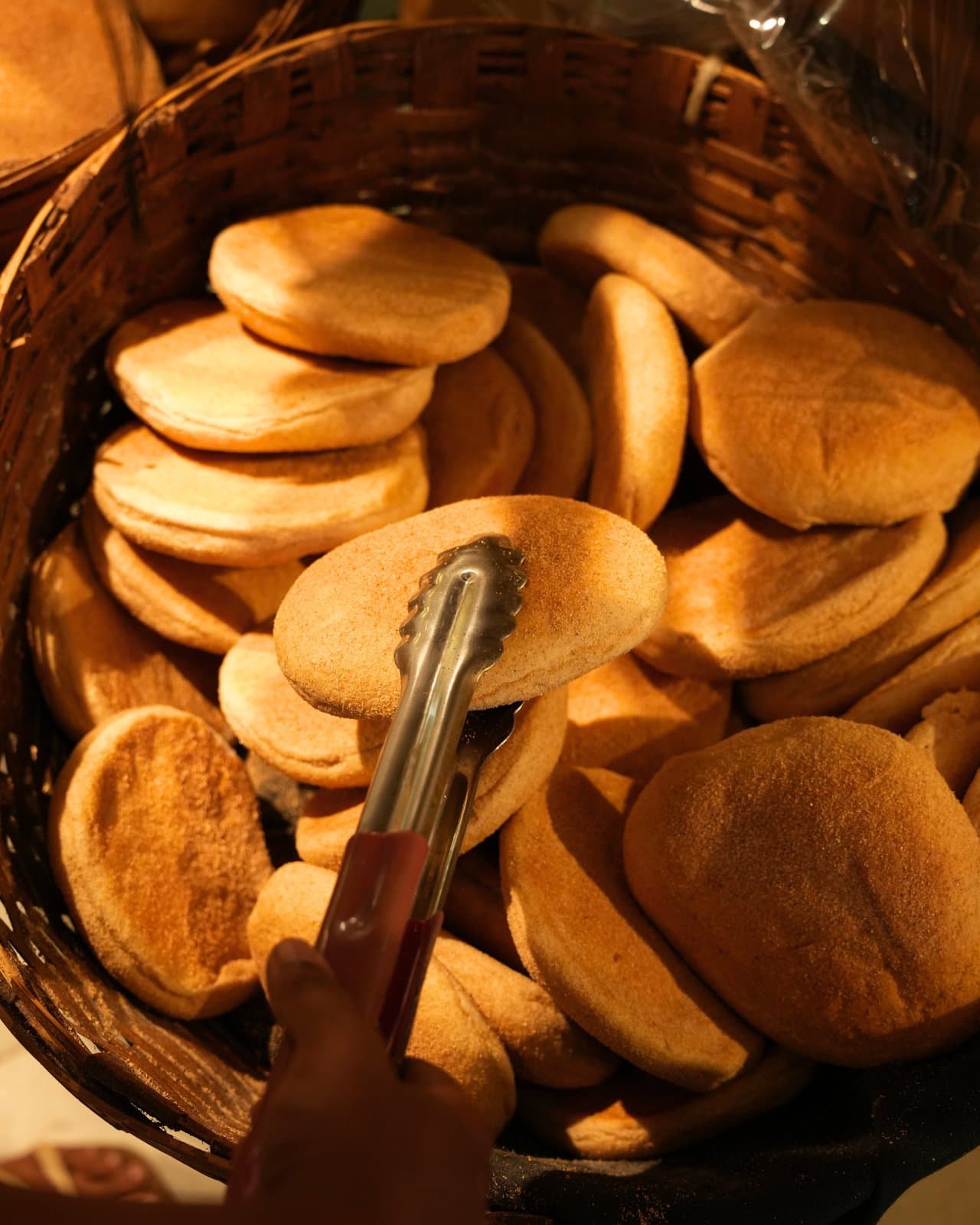 A basket of fresh buns, with tongs to pick them out