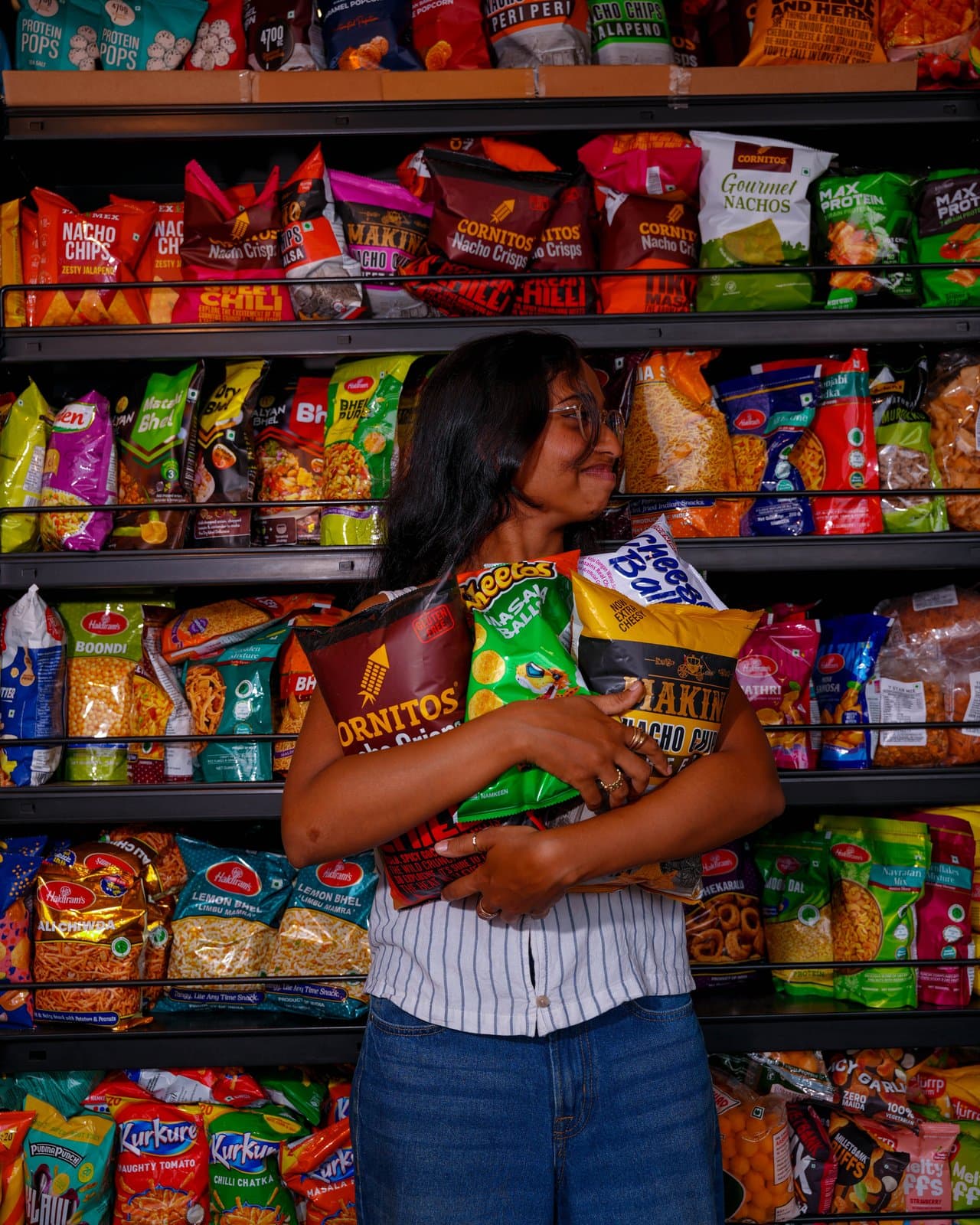 A shopper hugging an armful of snacks in the snack aisle