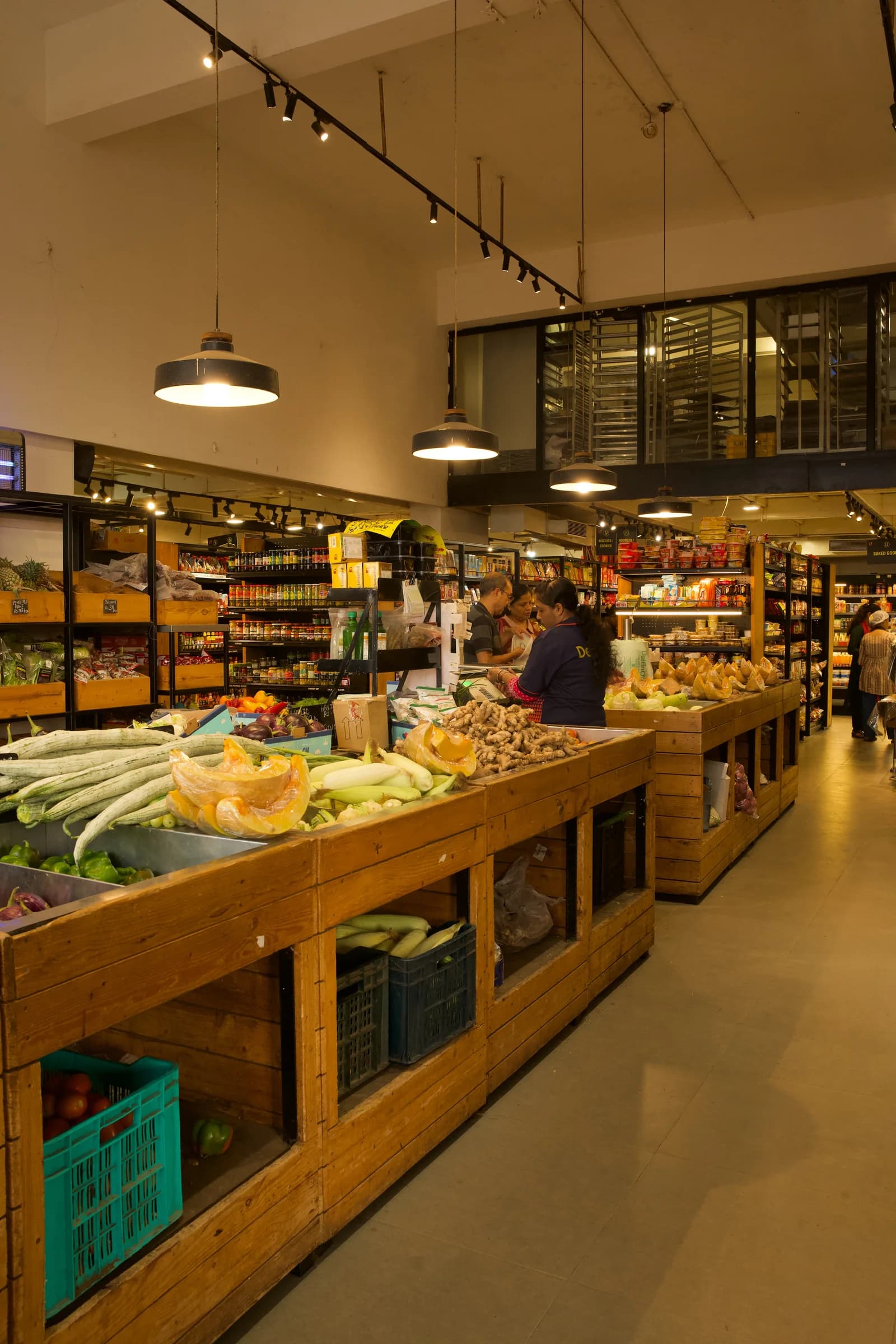Inside Delfino's, with wooden produce counters, stocked shelves and warm pendant lighting