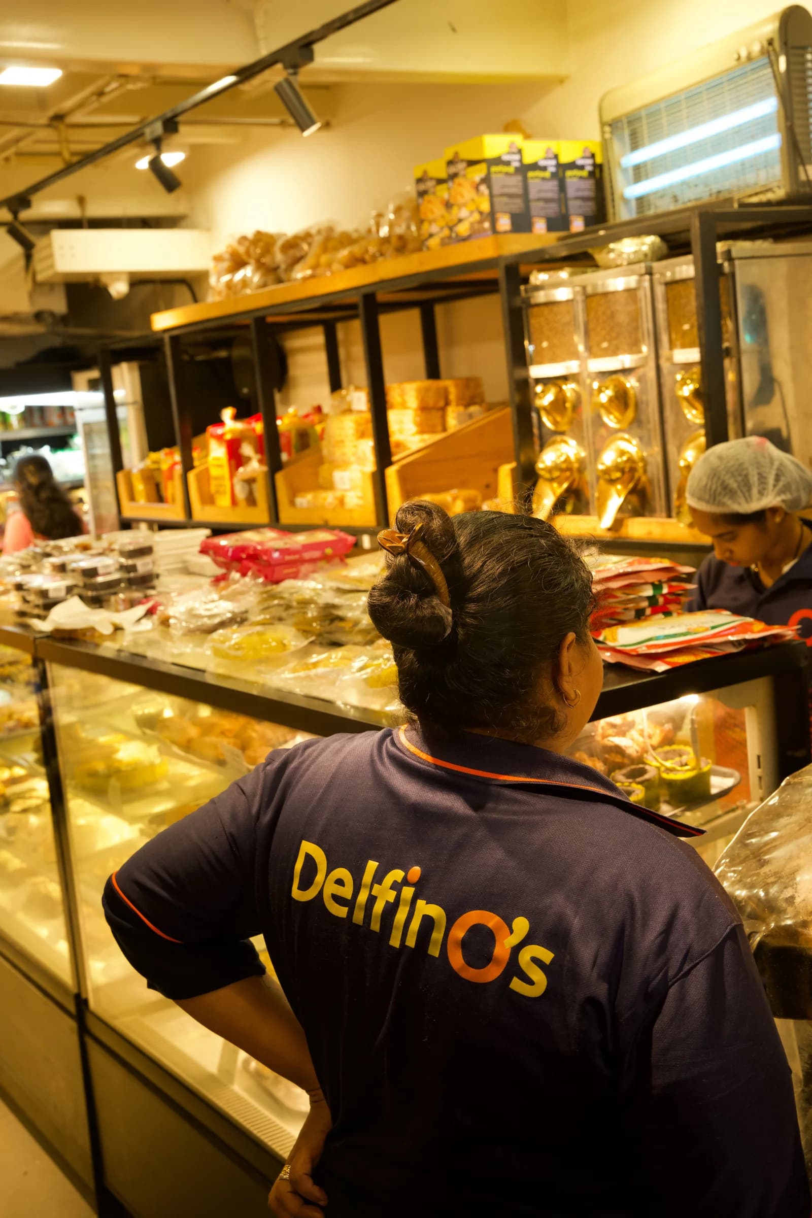 A Delfino's team member in the store uniform behind the bakery counter