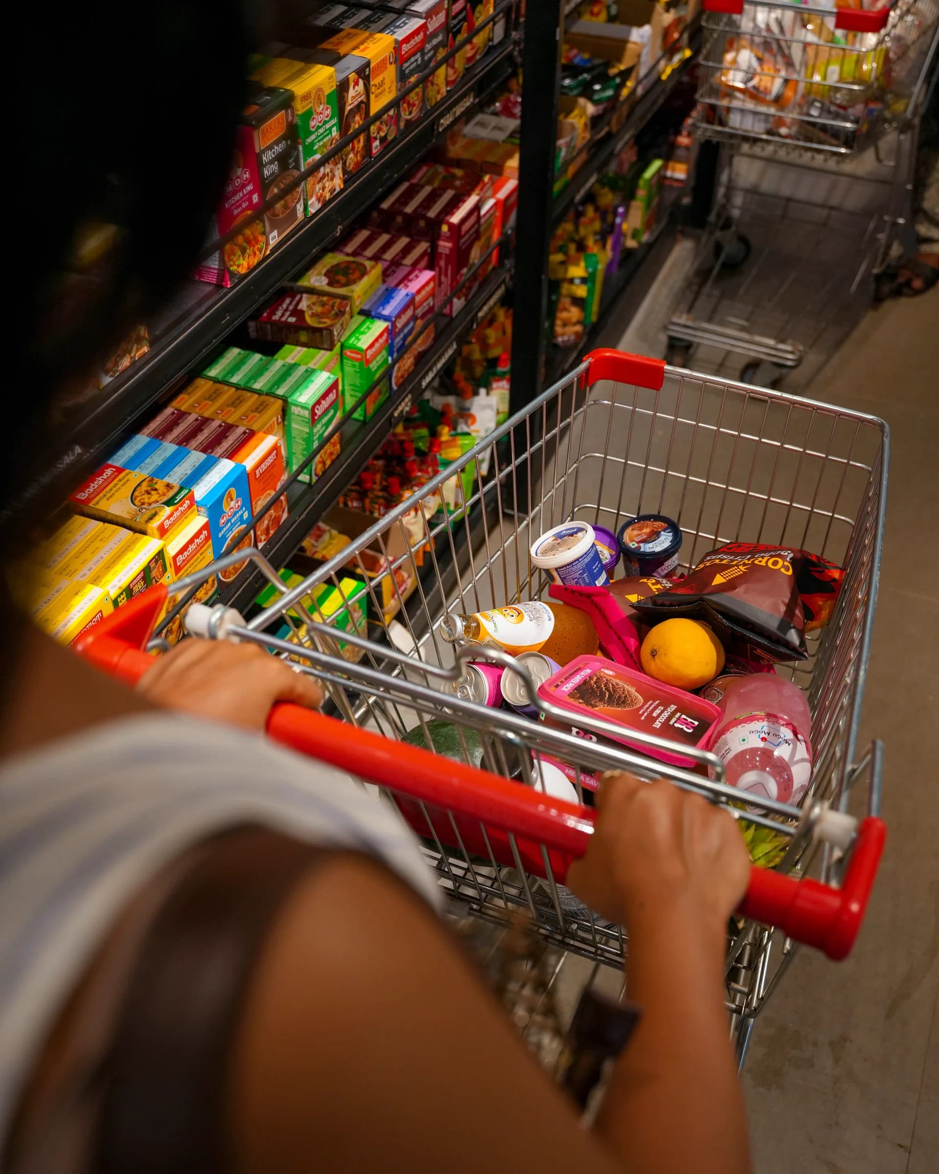 A shopper pushing a trolley of groceries down an aisle
