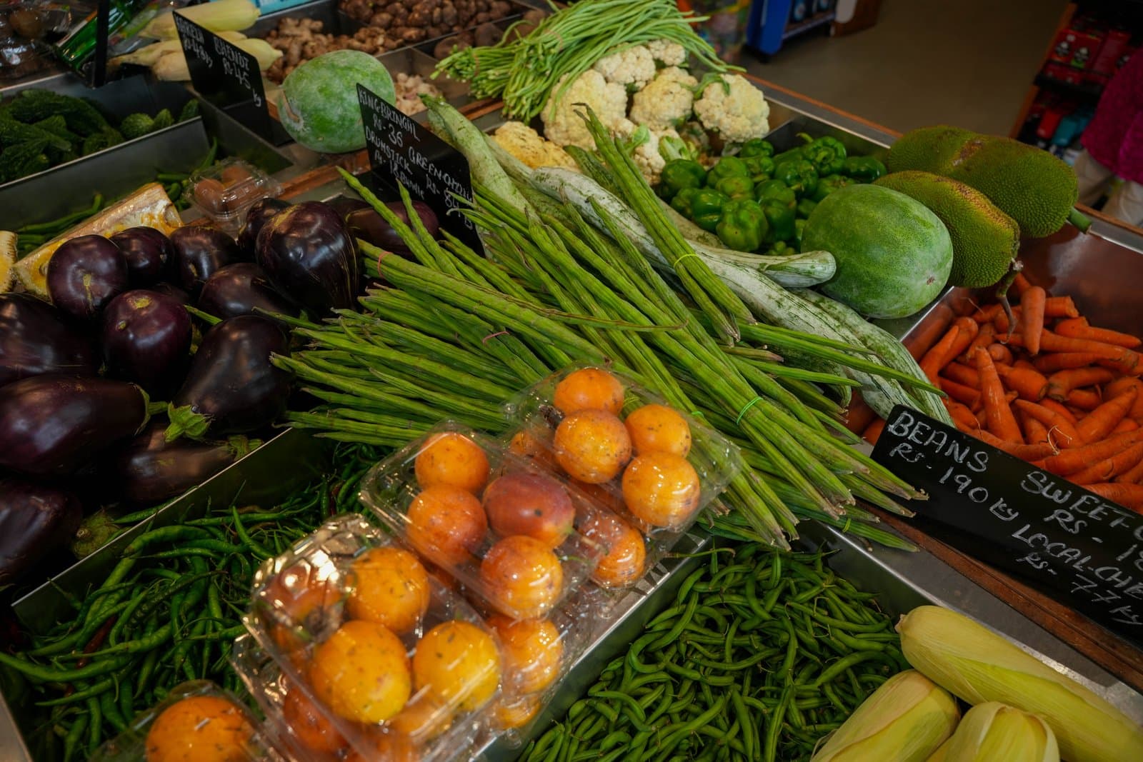 Aubergines, long beans, cauliflower and carrots on the vegetable counter